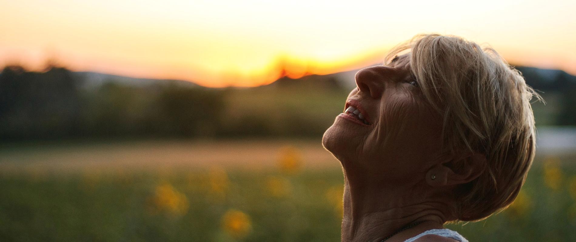 Vrouw staat buiten in de avondzon en haalt rustig adem
