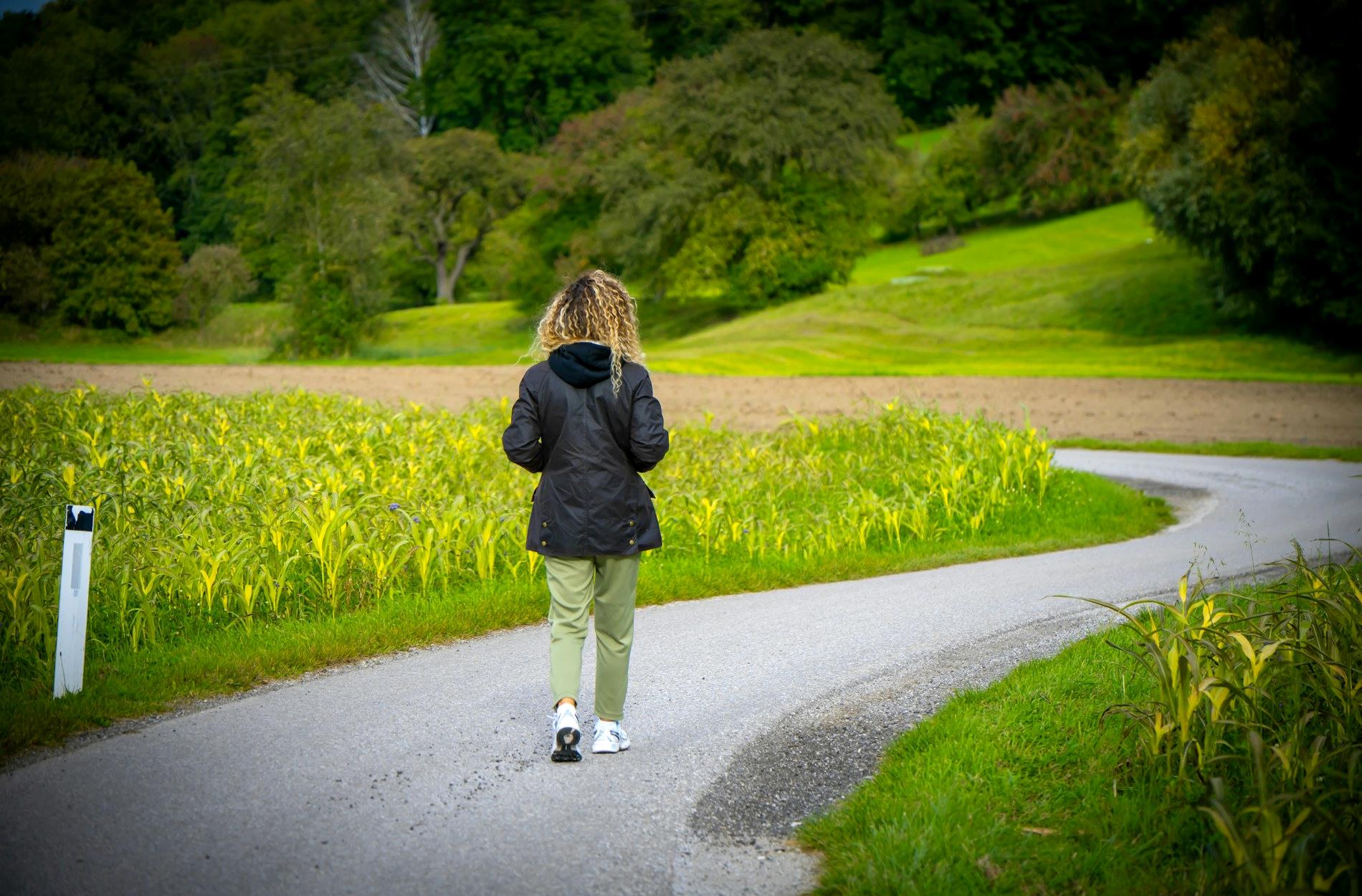 Vrouw wandelt over een landweg langs groene velden